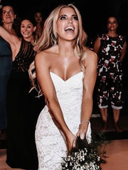 Bride wearing a strapless lace wedding dress by 27Dress holding a bouquet at celebration