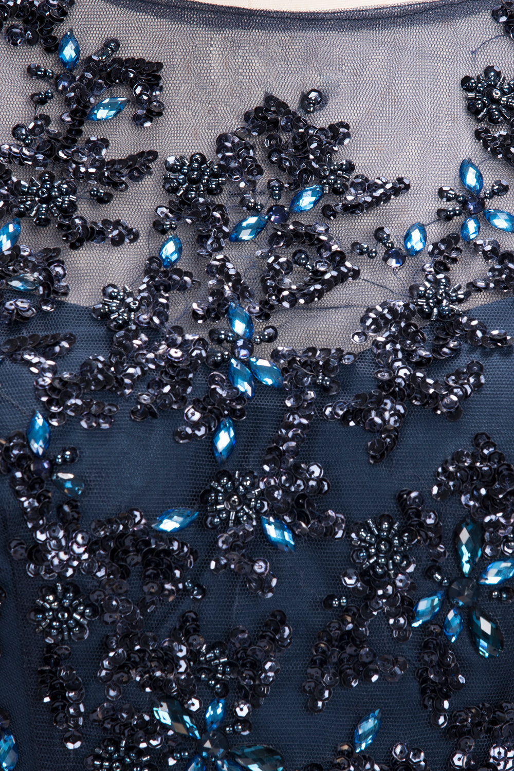Close-up of black mesh fabric with blue and black bead embellishments on formal evening dresses